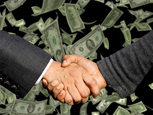 Two person shaking hands-with money on background